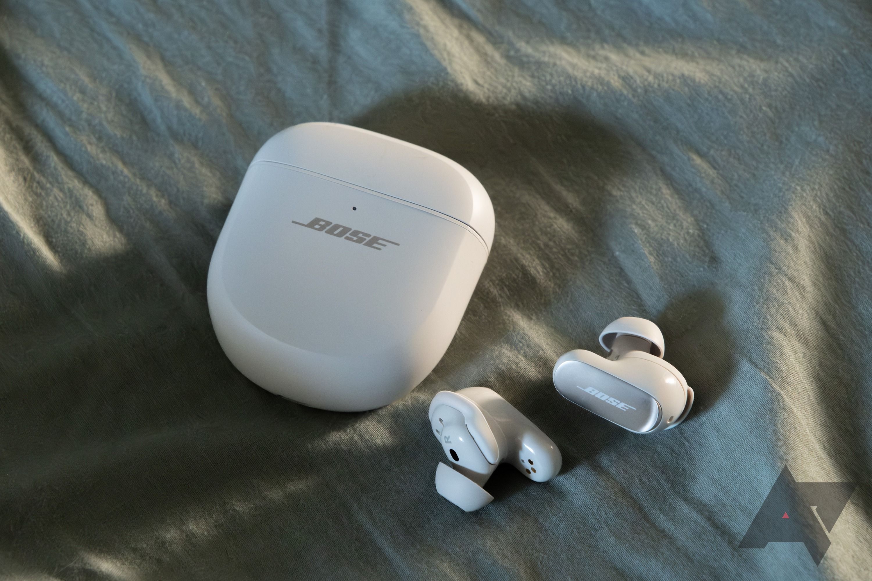 หูฟัง Bose สีขาวพร้อมเคสวางอยู่บนผ้า