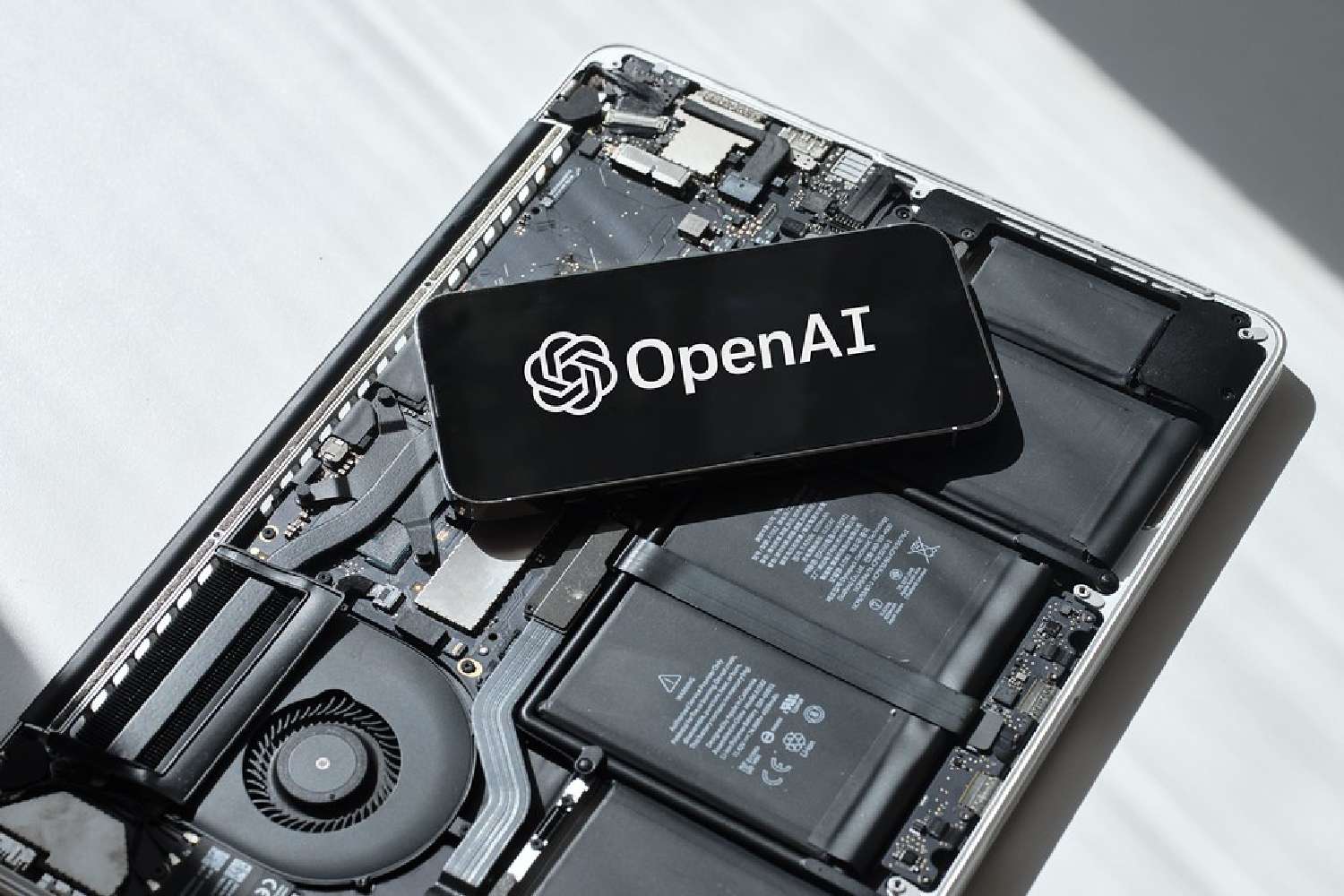 ภาพประกอบโลโก้ OpenAI วางอยู่บนแผงวงจรอิเล็กทรอนิกส์ สื่อถึงการพัฒนาฮาร์ดแวร์ของตัวเอง