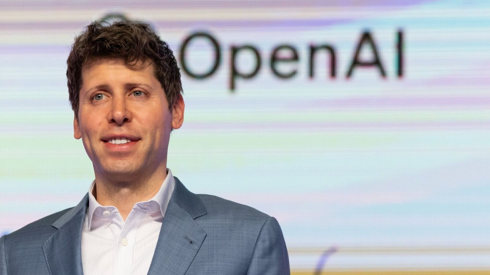 Sam Altman ซีอีโอของ OpenAI ต่อหน้าโลโก้บริษัท ในบริบทของการเตรียมเข้าตลาดหลักทรัพย์