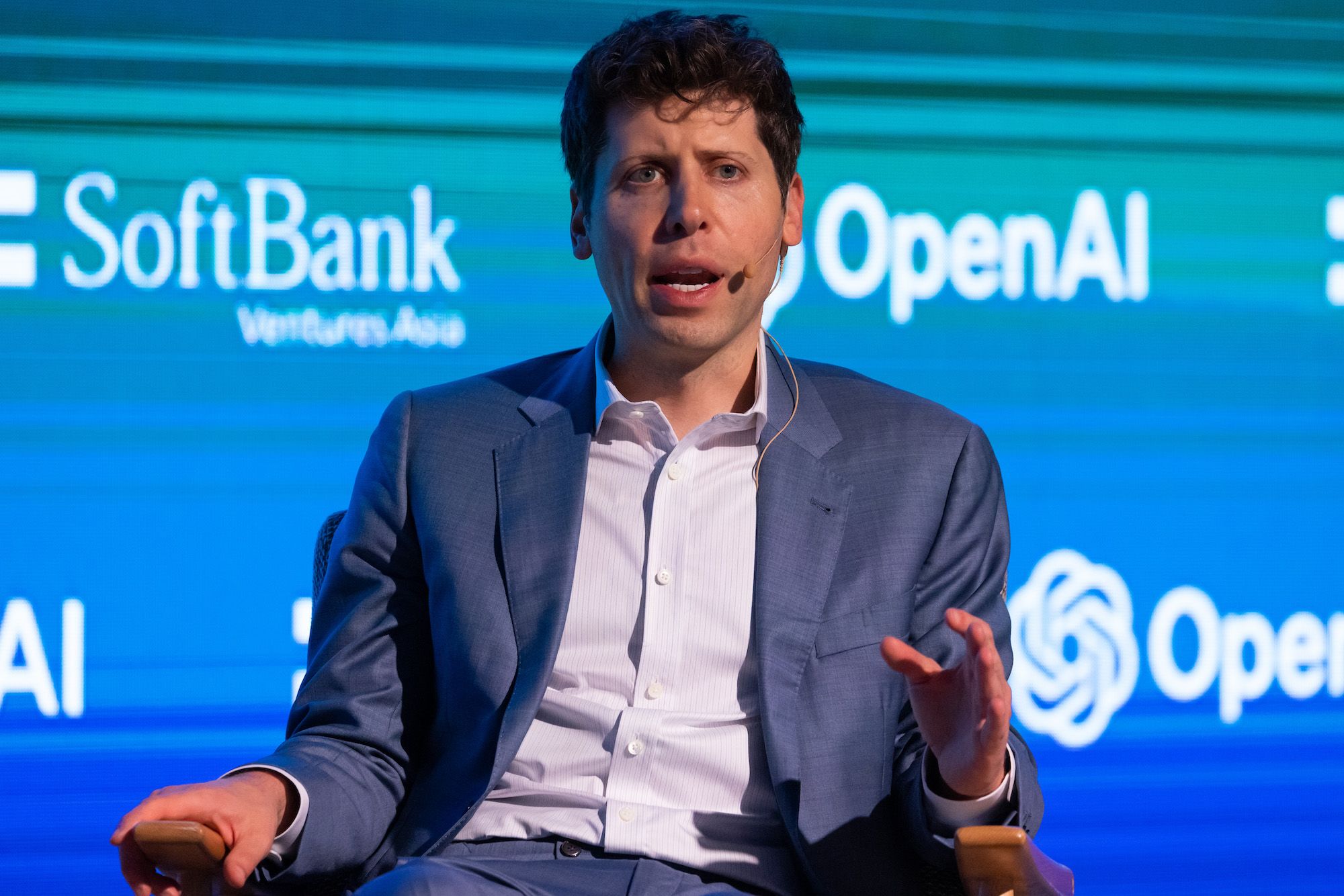 Sam Altman นั่งให้สัมภาษณ์บนเวทีงานที่มีโลโก้ SoftBank และ OpenAI ขึ้นจอด้านหลัง