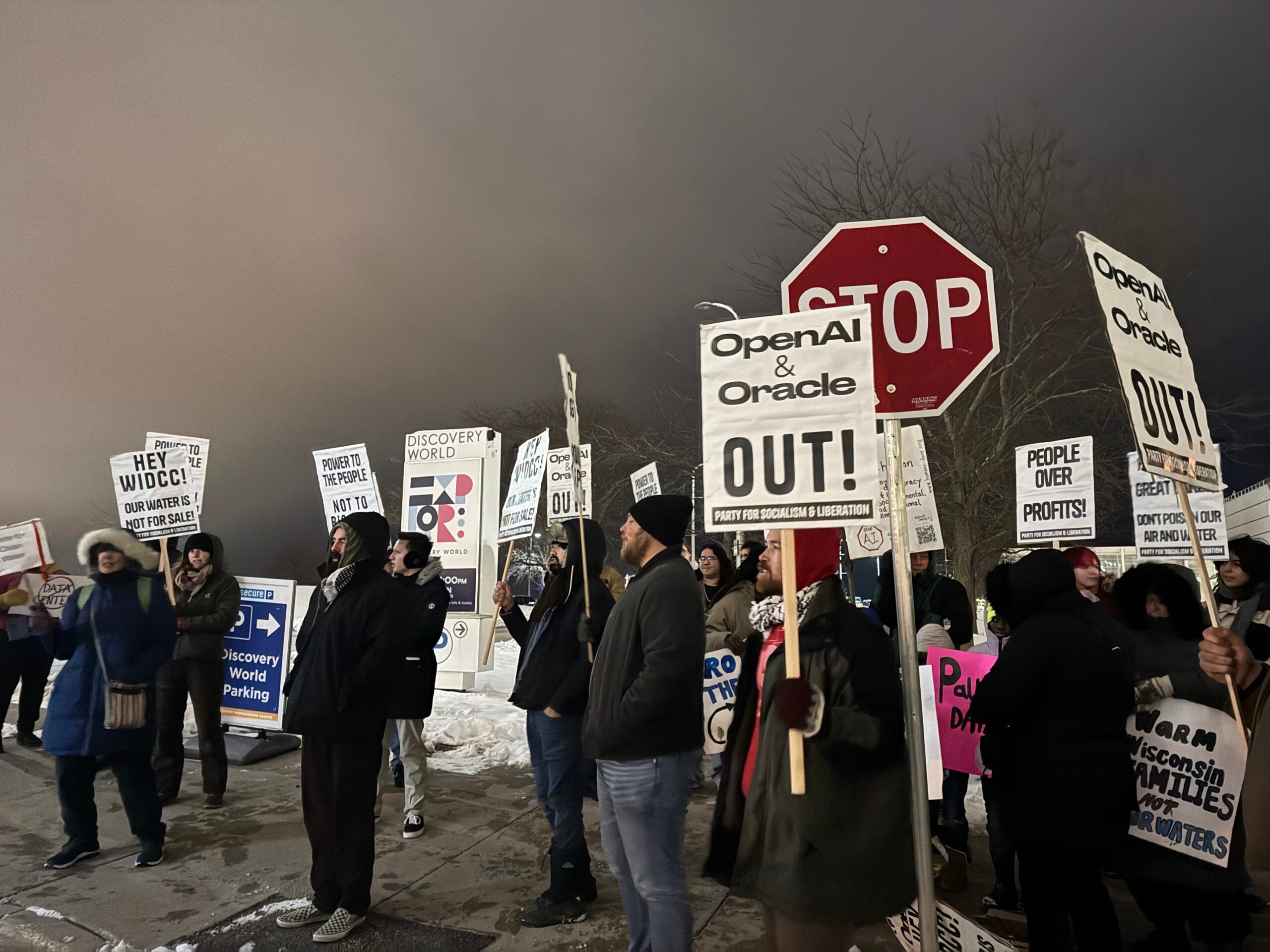 ผู้ประท้วงถือป้าย 'OpenAI & Oracle OUT!' และ 'People Over Profits' ในการชุมนุมต่อต้านดาต้าเซ็นเตอร์