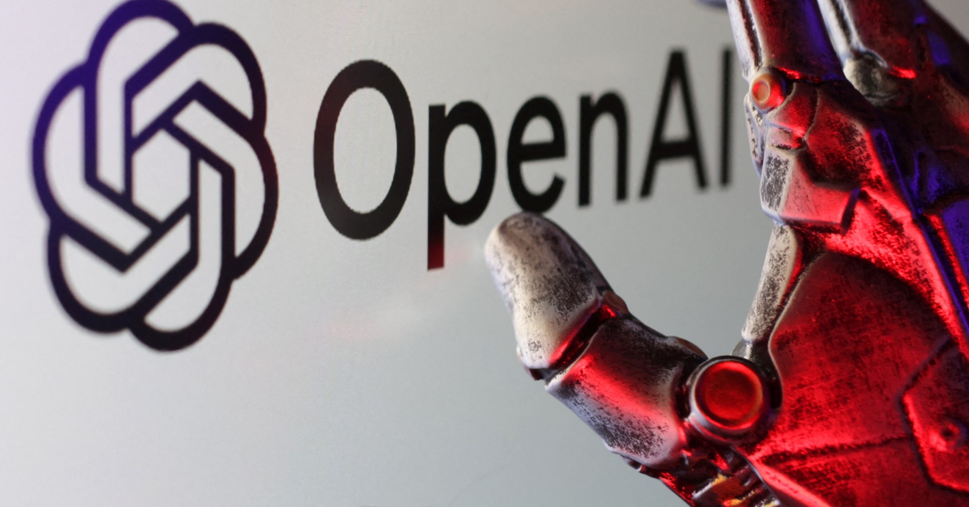 The OpenAI logo with a red robotic hand reaching toward it, evoking concerns about hard-to-control AI model behavior