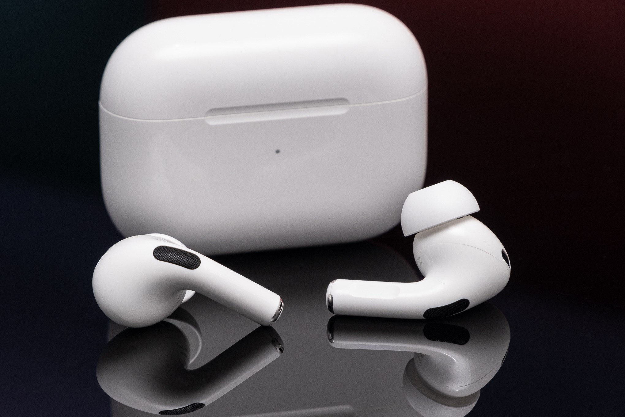 เคสชาร์จและหูฟังไร้สายตระกูล AirPods วางคู่กันบนพื้นผิวสะท้อนแสง